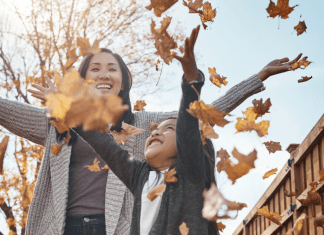 girl and woman throwing leaves in air